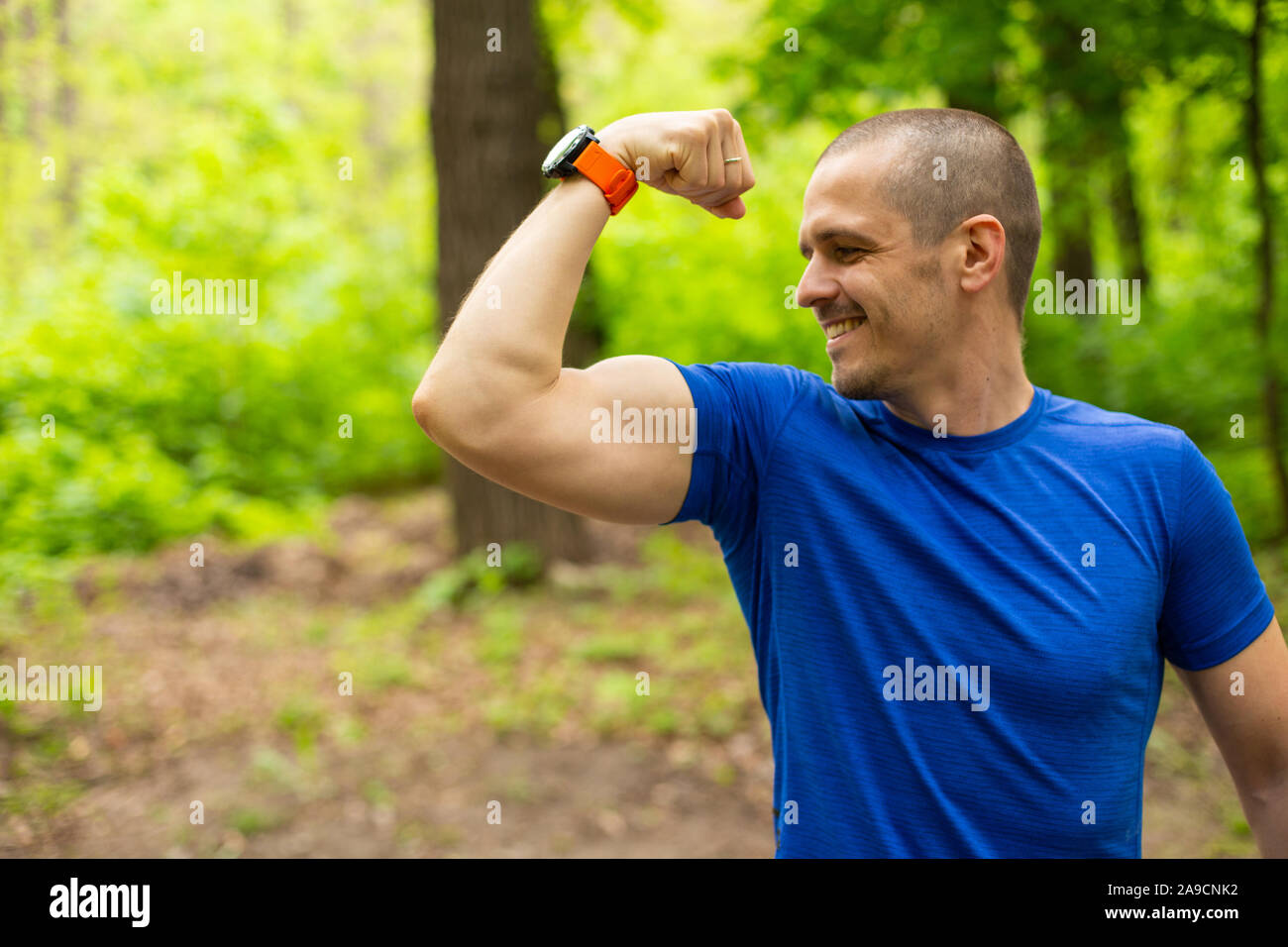 Lächelnd Athlet man show seinen Bizeps outdoor Stockfoto