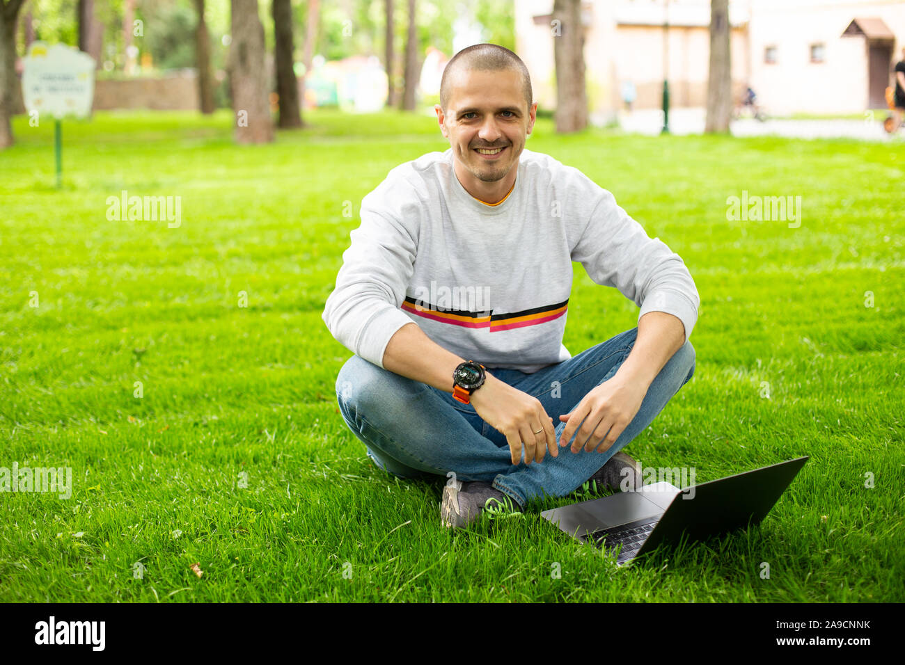 Freelancer Mann bei der Arbeit am Laptop sitzen auf Rasen Stockfoto
