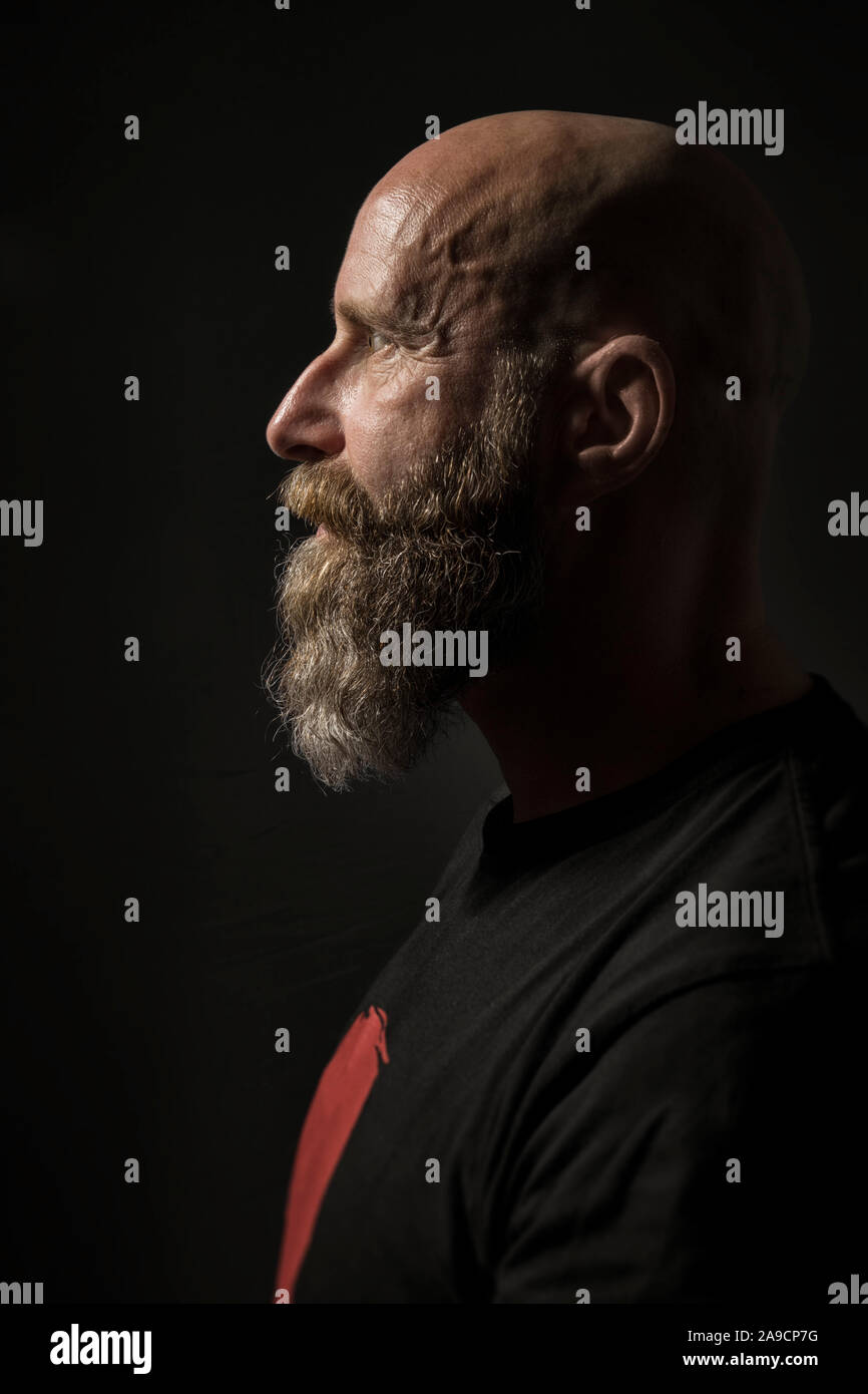 Ein Bild von einem bärtigen Mann mit Glatze Seitenansicht und dunklen Hintergrund Stockfoto