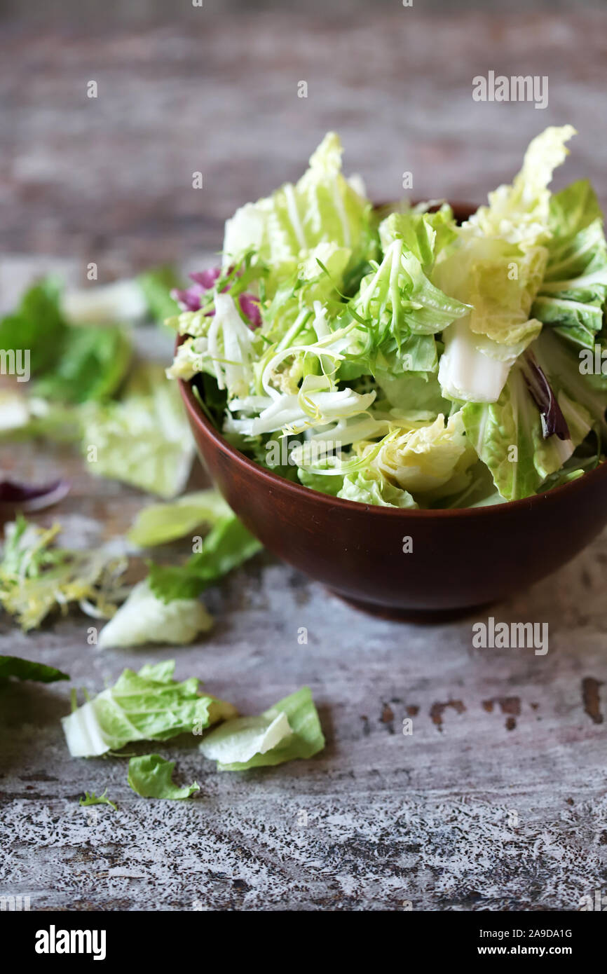 Mischung von Salaten in eine Schüssel geben. Grüne saftige Salatblätter. Das Konzept der gesunden Ernährung. Selektive konzentrieren. Makro. Stockfoto