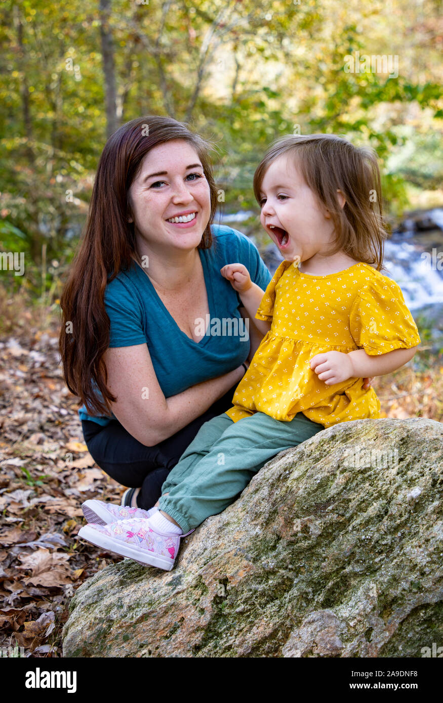 Tochter ist dumm schreiend am Wasserfall mit Mutter immer noch lächelnd Stockfoto