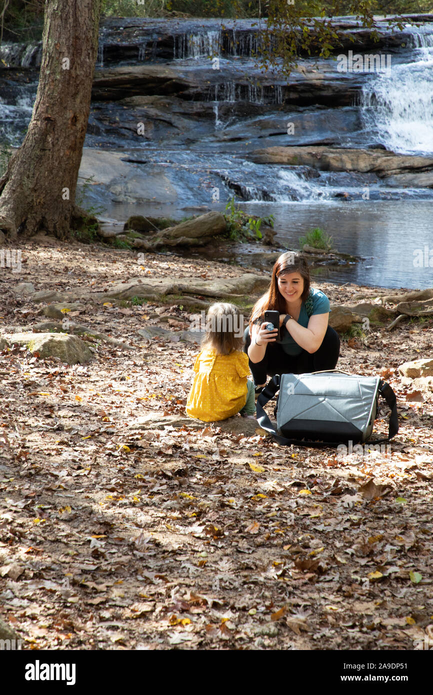 Mutter, die Tochter mit einem Handy mit Wasserfall im Hintergrund fotografiert Stockfoto
