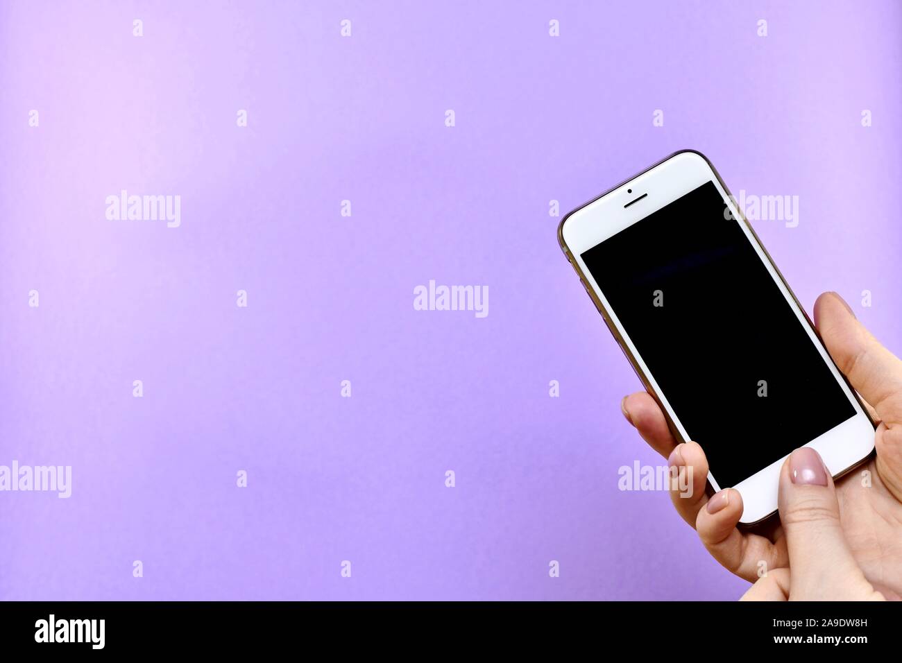 Ein Smartphone mit einem schwarzen Bildschirm ausgeschaltet in der Hand, eine Taste mit dem Daumen gedrückt wird, hinterlässt. Stockfoto
