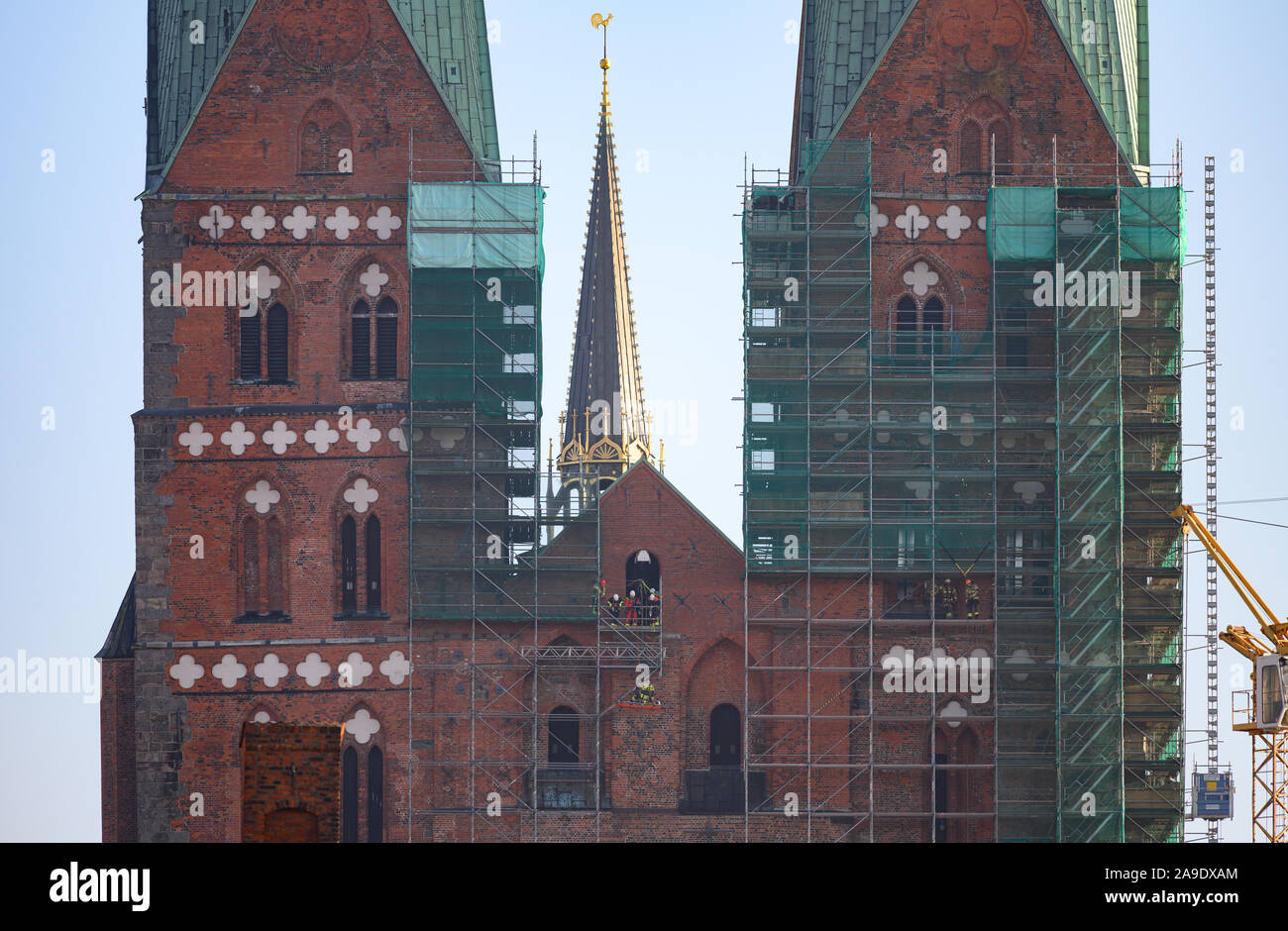 14 November 2019, Schleswig-Holstein, Lübeck: Feuerwehrleute (M) Zug der Rettung von Personen auf dem Gerüst auf der Westseite der Lübecker Marienkirche. Am 15. November, der 1,5 Millionen Euro Sanierung der Türme von St. Marien beginnt. Im oberen Teil der Türme gibt es Daumen dick und bis zu 70 Zentimeter tiefe Risse, die werden jetzt von Maurer der Kirche Gebäude Hütte geschlossen werden. Die Fertigstellung ist bis zum Sommer 2021 geplant. Foto: Rainer Jensen/dpa Stockfoto