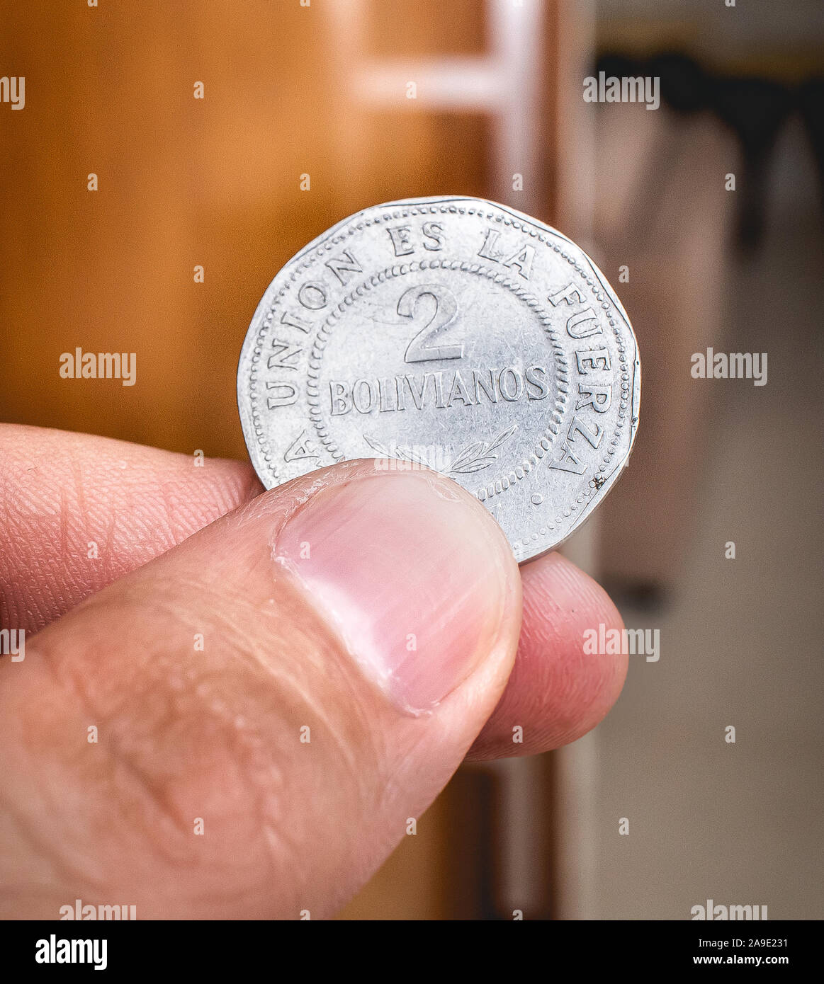 Bolivianischen Währung. Bild der Mann hält eine 2 bolivianischen Münze. Stockfoto