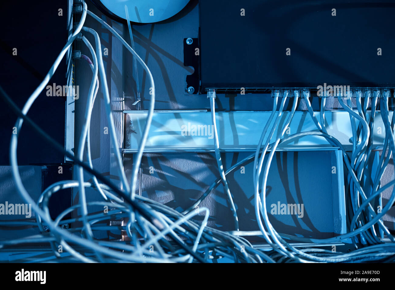 In der Nähe von computer system mit weißen Kabel an der Wand hängen in dunklen Büro Stockfoto