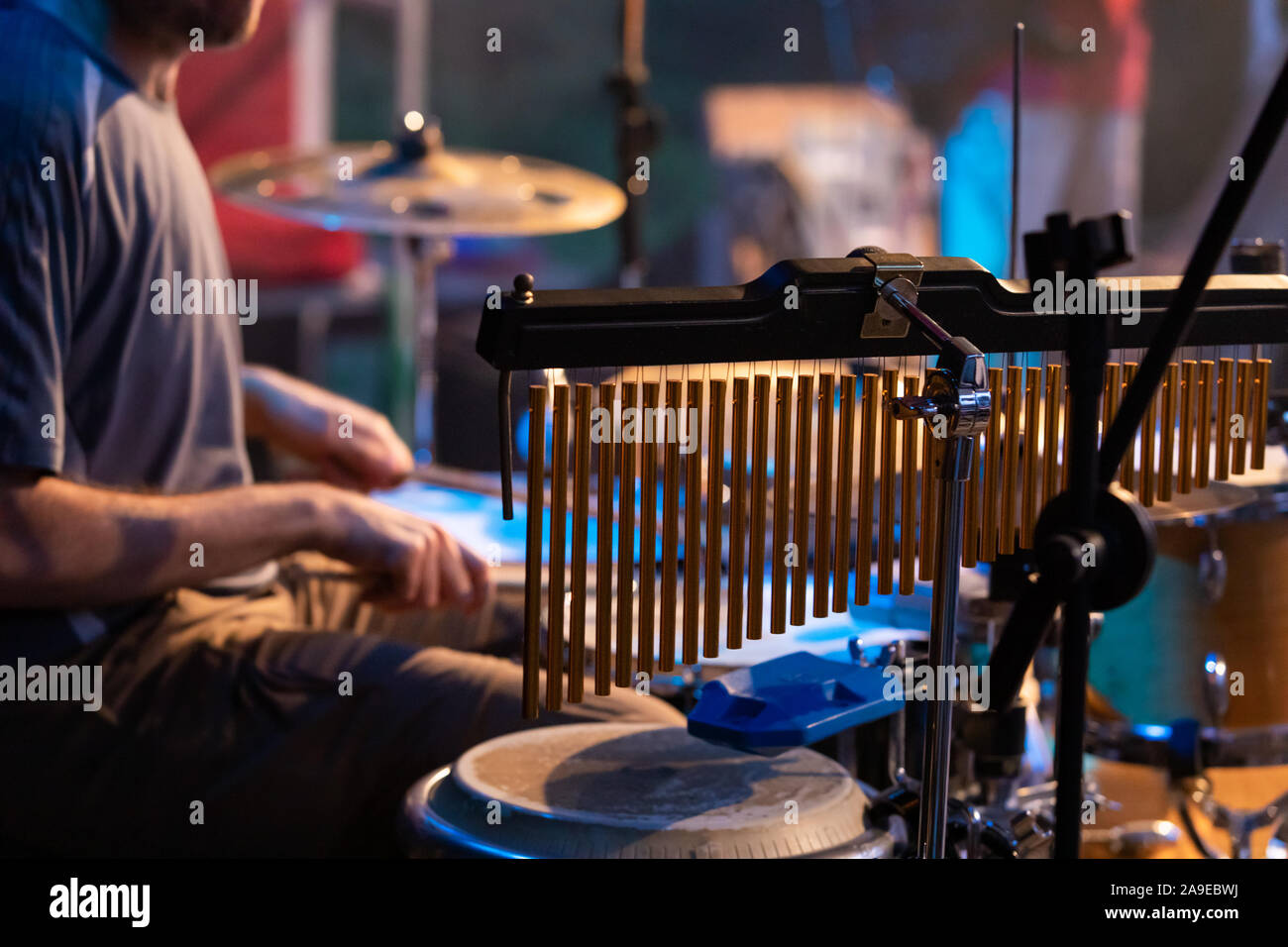 Eine selektive Ausrichtung und Blick auf professionelle bar Glockenspiel, Schlagzeug Zubehör, verschwommenen Blick auf einen Mann spielt Schlagzeug im Hintergrund Stockfoto