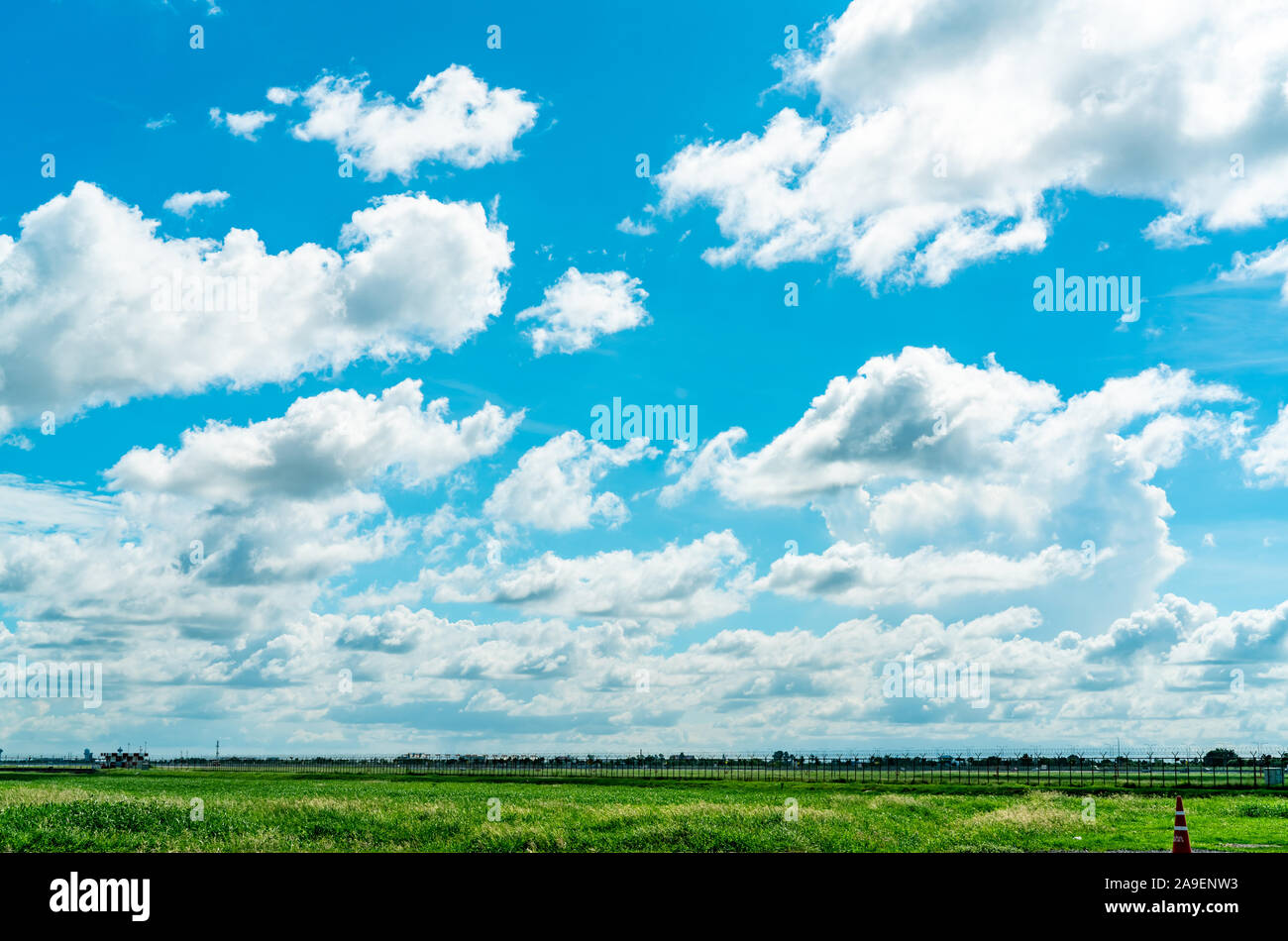 Landschaft grüne Rasenfläche und Zaun des Flughafens und schönen blauen Himmel und weiße flauschige Wolken. Schönes Wetter. Natur Landschaft. Bereich um Stockfoto