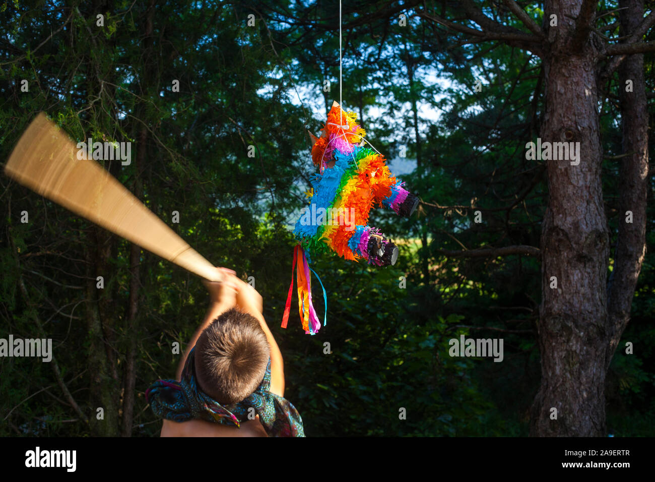 Ein Junge mit verbundenen Augen schlagen ein Pinata mit einem Stock Stockfoto