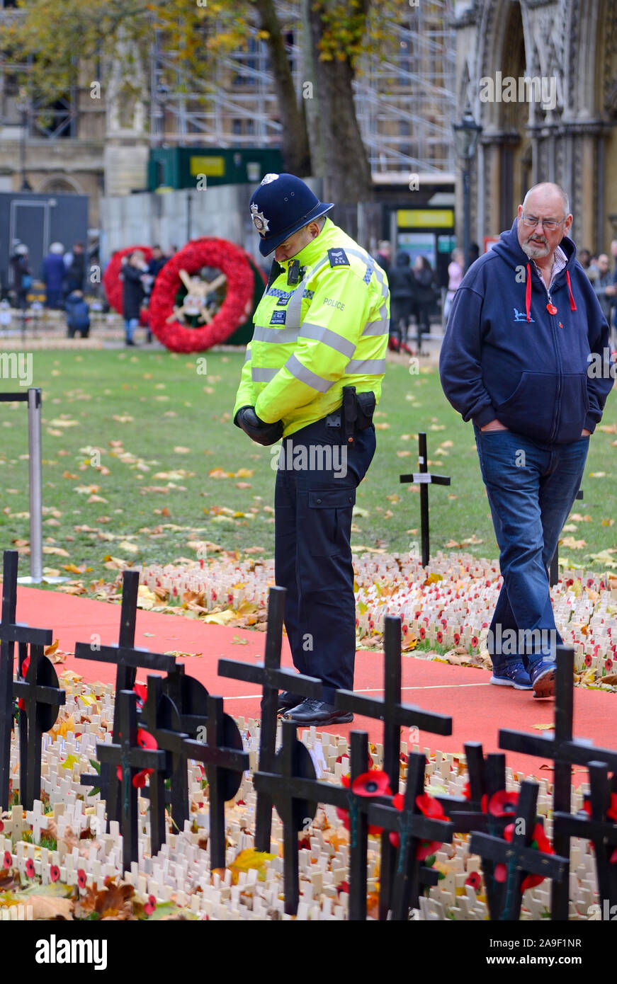 London, England, UK. Police Officer bei Mohn und Kreuze in den Garten von Westminster Abbey auf der Suche vor Rememberence Sonntag Stockfoto