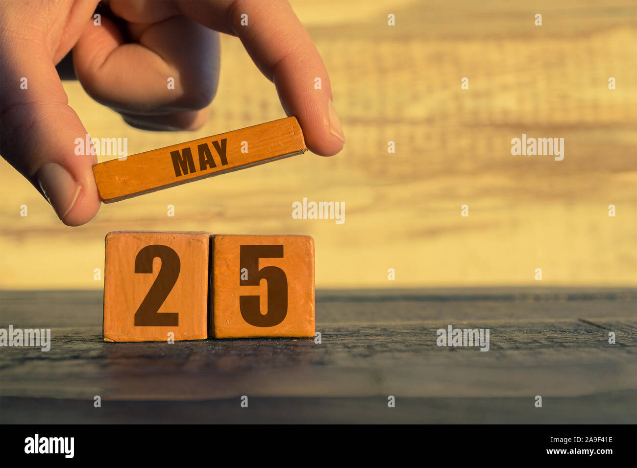 25. Mai. Tag 25 Monat, Kalender auf einem holzwürfel. die Hand einer Frau wird der Name des Monats auf die Zahl des Monats auf einer hölzernen Hintergrund spri Stockfoto