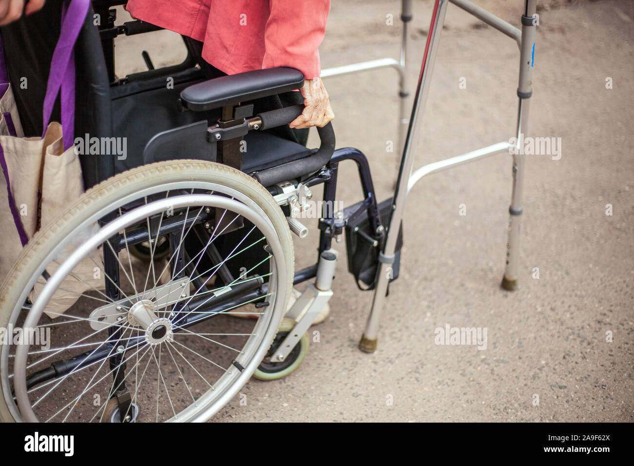 Rollstuhl Rollstuhl auf der Straße. Soziale Hilfe für Menschen mit Verletzungen des Bewegungsapparates. Bequeme Sessel für den Transport von INAKTI Stockfoto