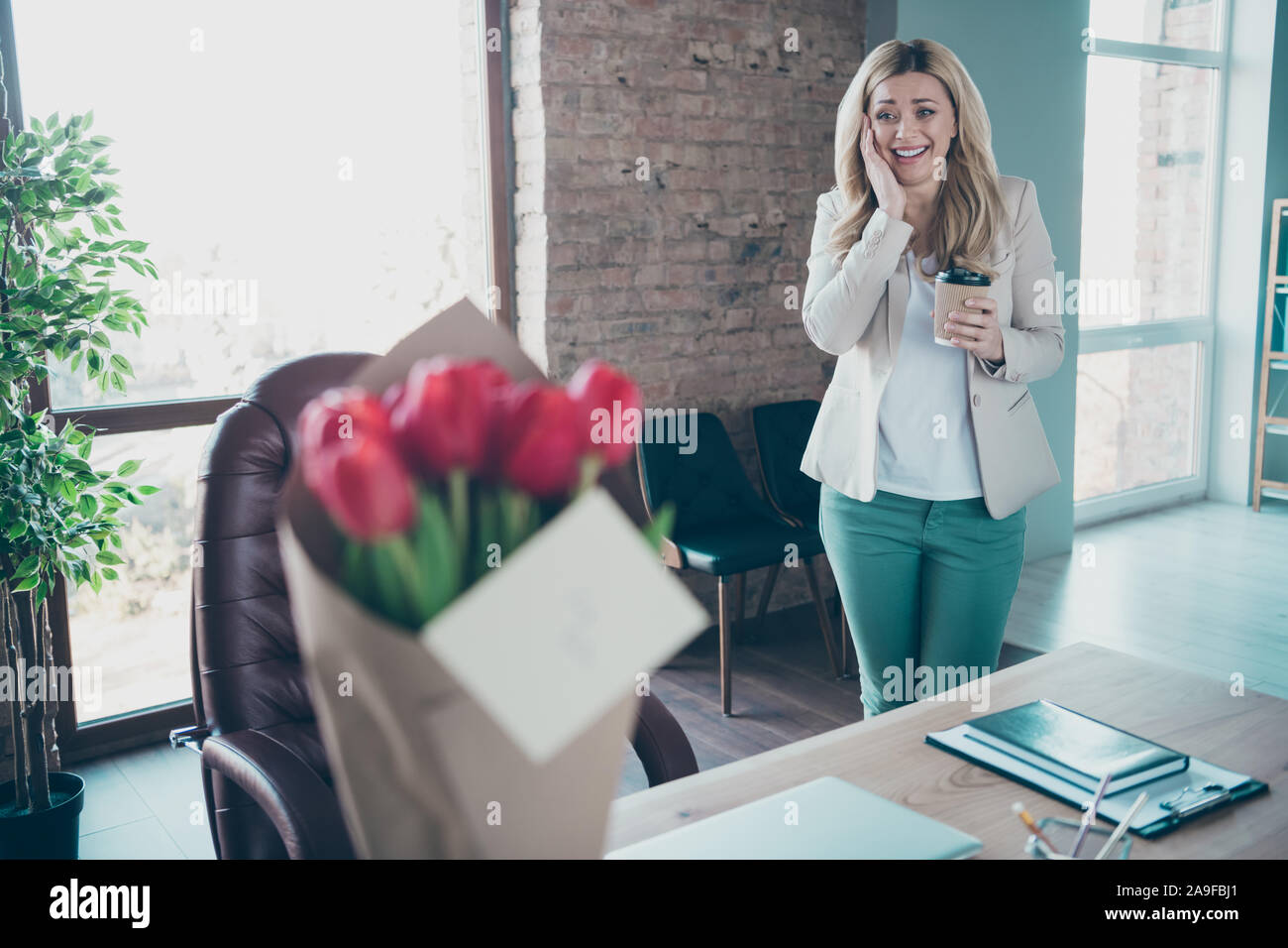 Foto der schönen blonden business lady kam Arbeitsplatz Holding takeaway Kaffee erstaunt frische Tulpen Bündel kleine Postkarte fremder geheimer Bewunderer auf Stockfoto