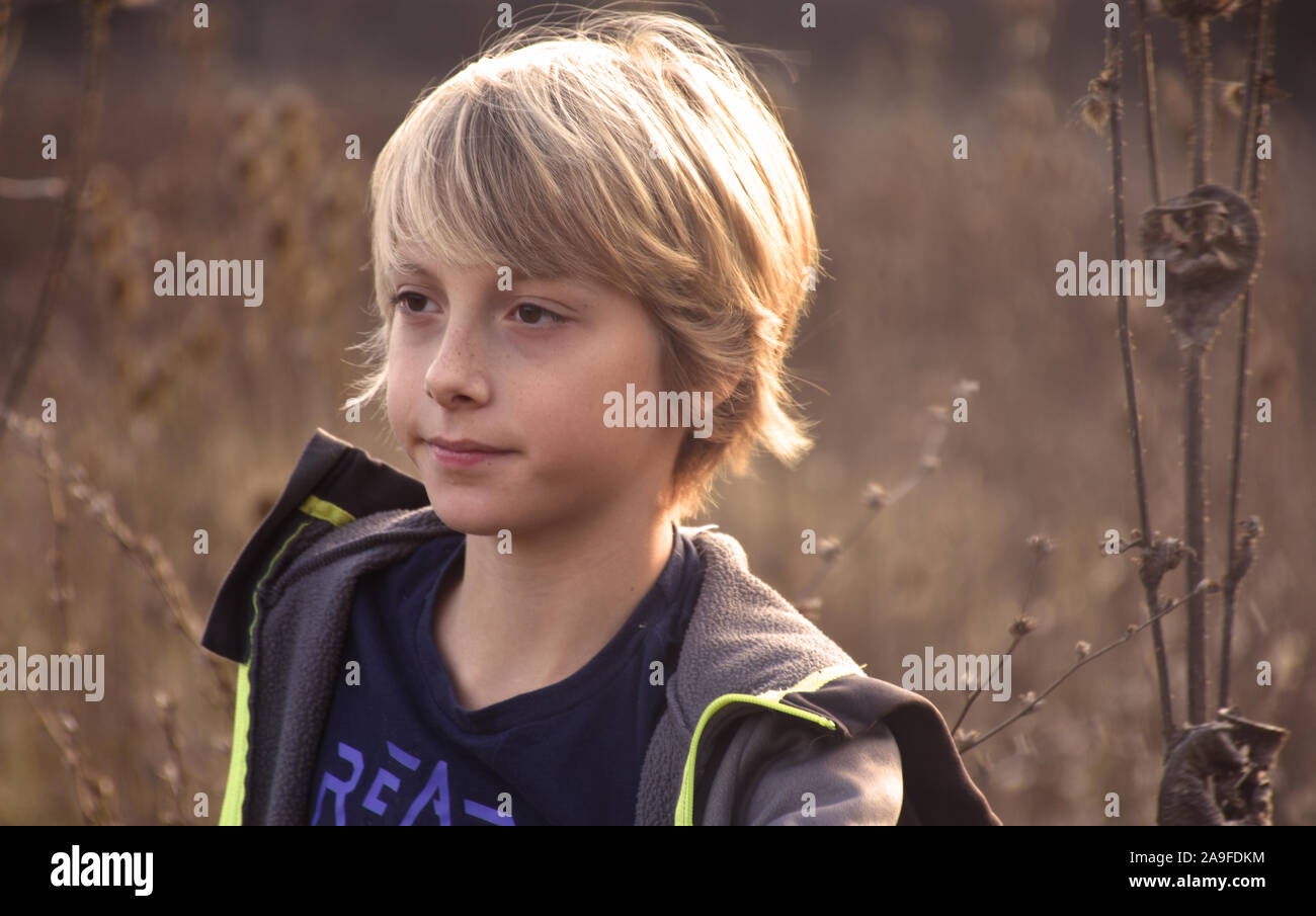 Close up Portrait von schöner Junge mit langen blonden Haaren im Herbst Feld Stockfoto