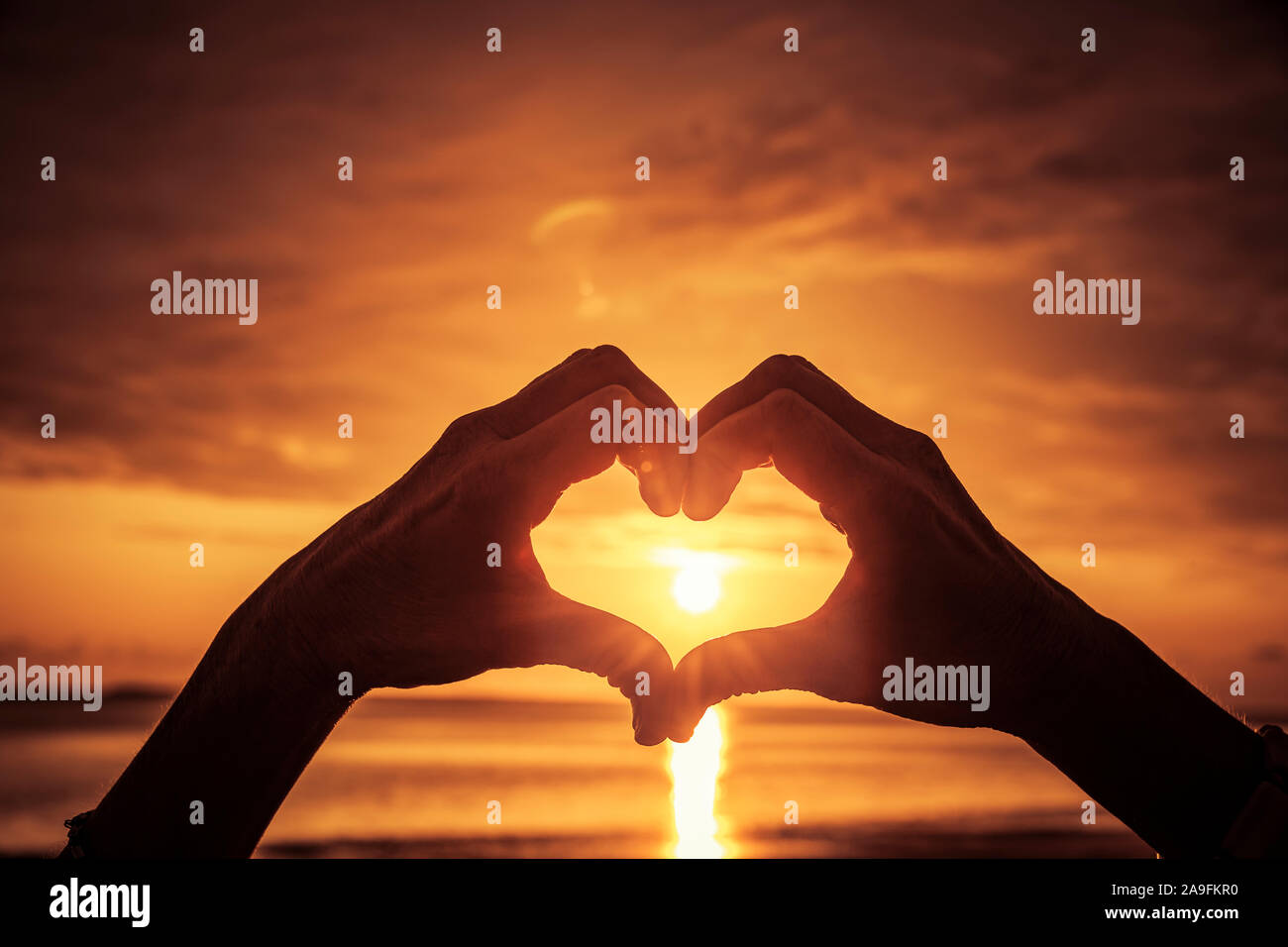 Hand als Herzform bei Sonnenuntergang Stockfoto