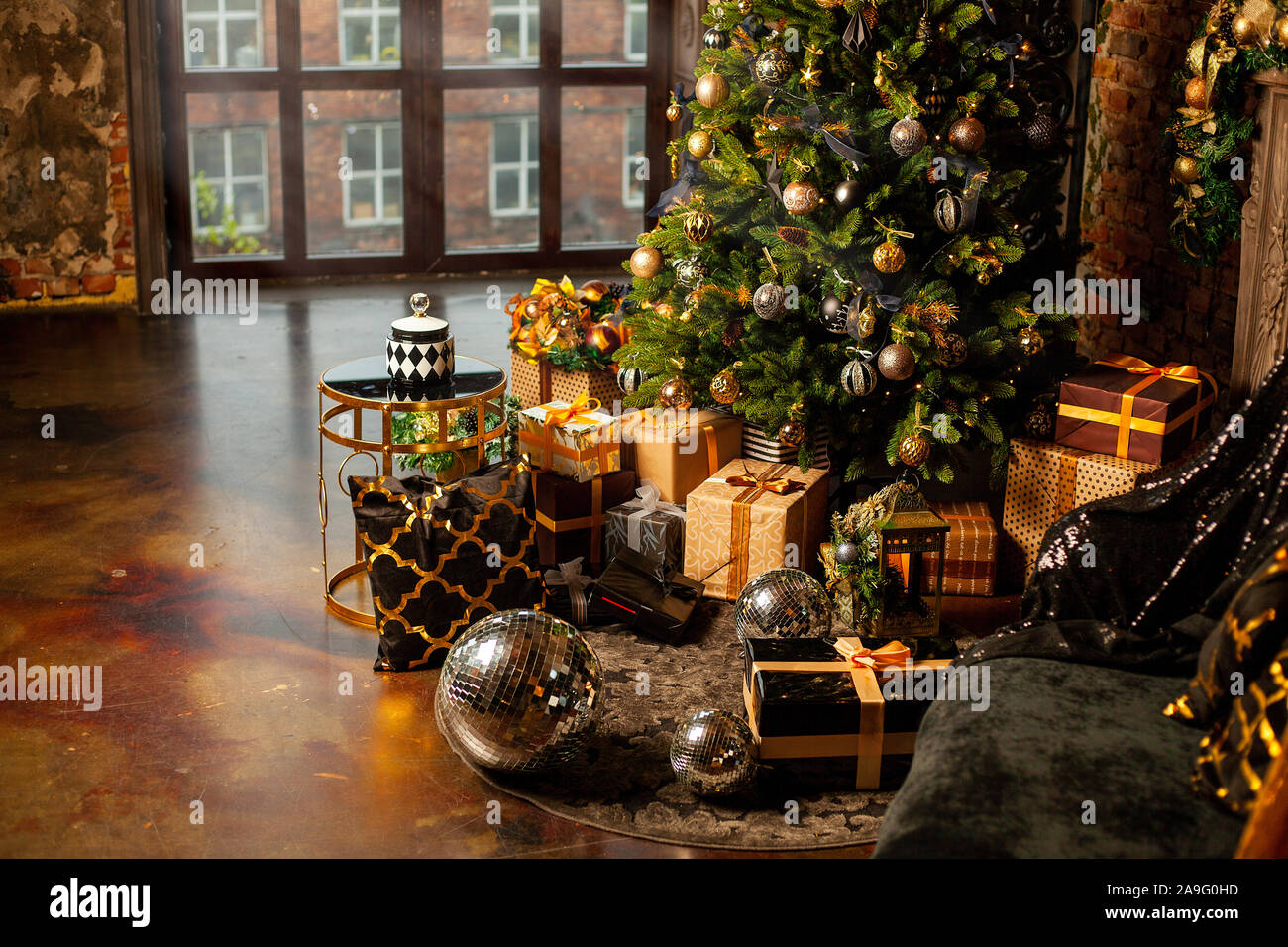 In der Nähe eines Weihnachtsbaumes mit goldenen Kugeln dekoriert. Unter dem Weihnachtsbaum eine große Anzahl der Weihnachtsgeschenke. Weihnachten Konzept. Eine riesige Stockfoto