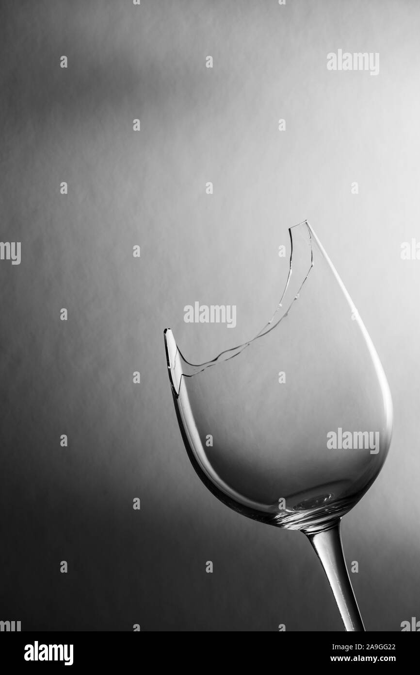 Studio closeup oblique Ansicht einer zerbrochenen Glas Wein vor der strukturierten Hintergrund mit weichen Licht dunkel Gradient monochrom. Stockfoto