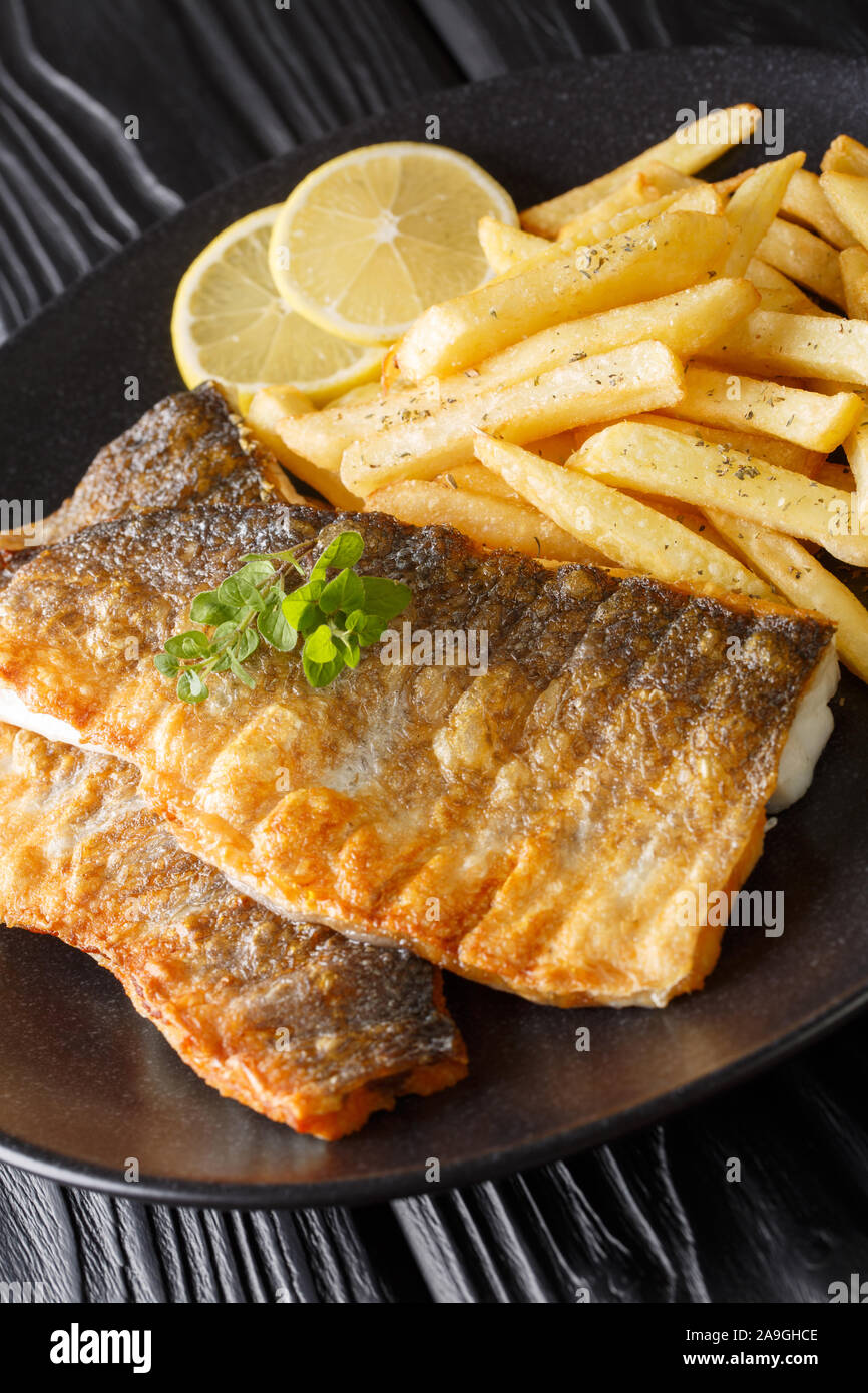 Gegrilltes Barschfilet mit Pommes frites Close-up auf einem Teller auf den Tisch. Vertikale Stockfoto