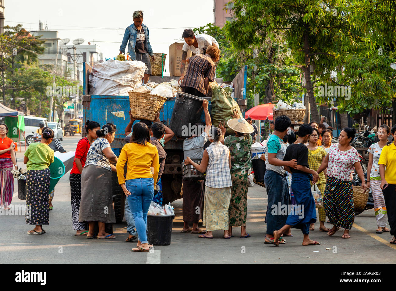 Die lokale Bevölkerung Pass, ihren Abfall/Müll auf eine Garbage Collection Lkw, Mandalay, Myanmar. Stockfoto