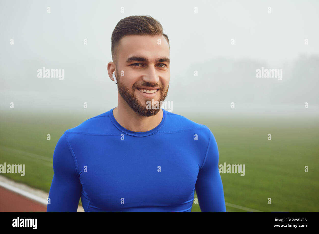 Sport Kerl in blauer Kleidung lächelt, während im Stadion im Nebel auf der Suche Stockfoto