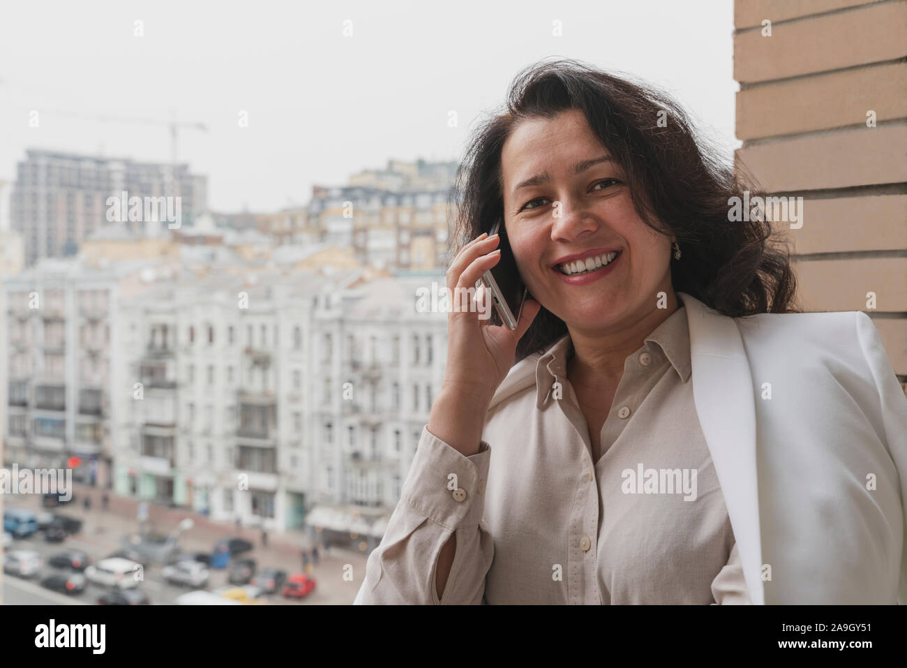 Fröhliche brunette Unternehmer ist, am Telefon zu sprechen auf dem Balkon. Flexible Arbeitszeiten und Telearbeit Konzept Stockfoto