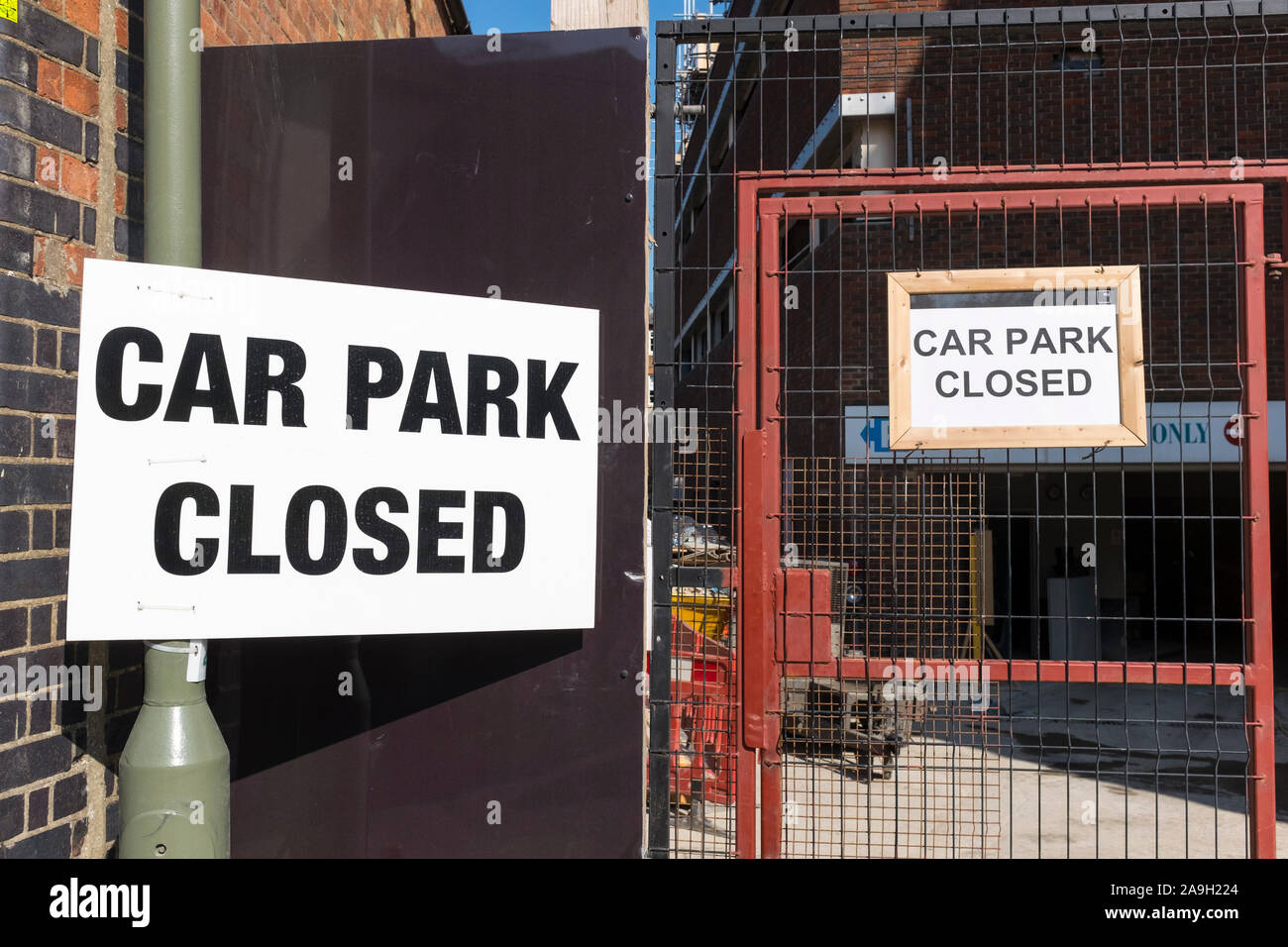 Zwei Parkplatz Schilder zeigen' Parkplatz geschlossen' an ein Fallrohr und metall draht Tor befestigt Stockfoto