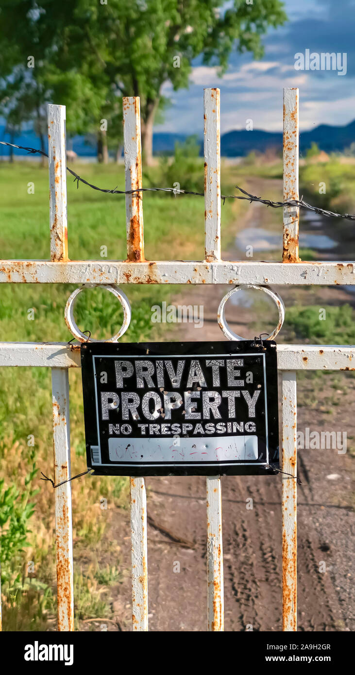 Vertikale Privateigentum Zeichen auf einem alten verrosteten weißen Tor mit Kette und einem Vorhängeschloss gesichert Stockfoto