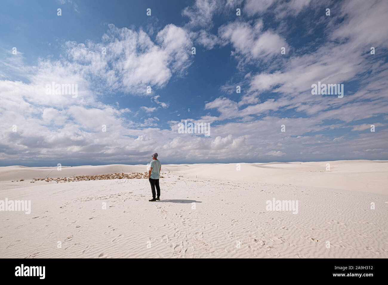 Mann in Freizeitkleidung inmitten der weißen Sanddünen gegen den blauen Himmel Stockfoto