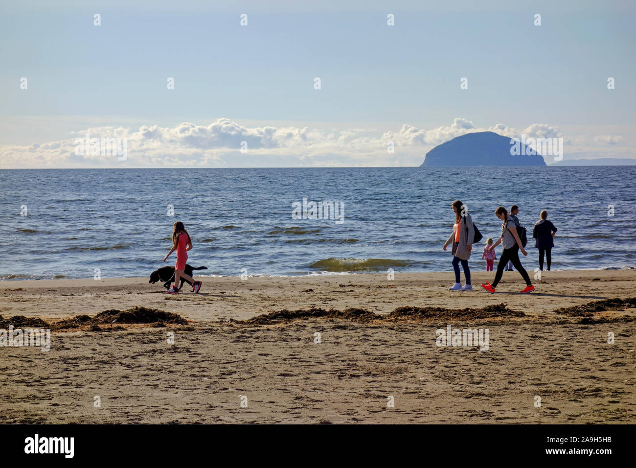 Menschen zu Fuß am Strand von Girvan in South Ayrshire, Schottland mit Ailsa Craig in der Ferne. Stockfoto