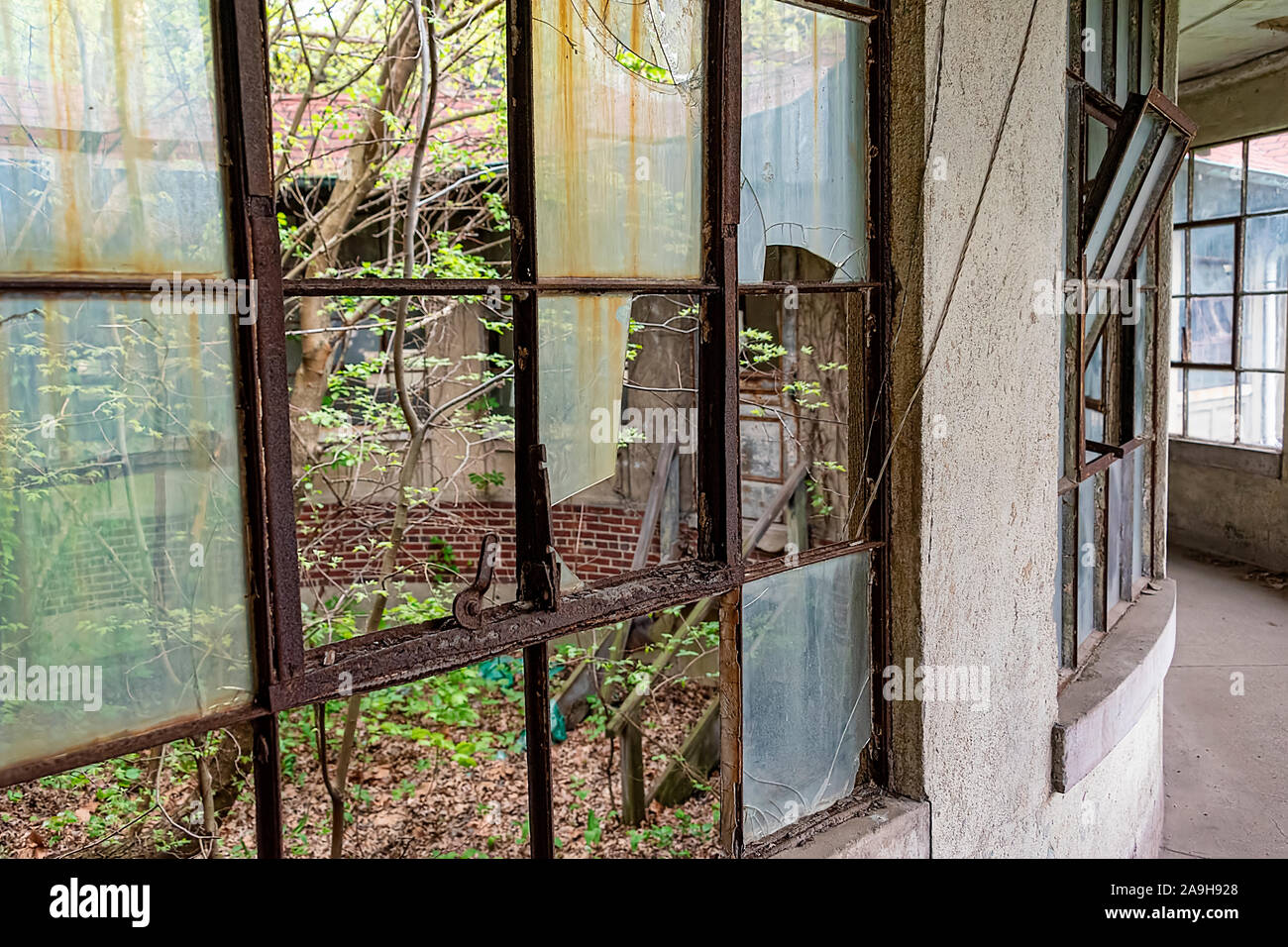 USA, New York, Ellis Island - Mai 2019: Zerbrochene Fenster in den Korridor von einem verlassenen Krankenhaus Stockfoto