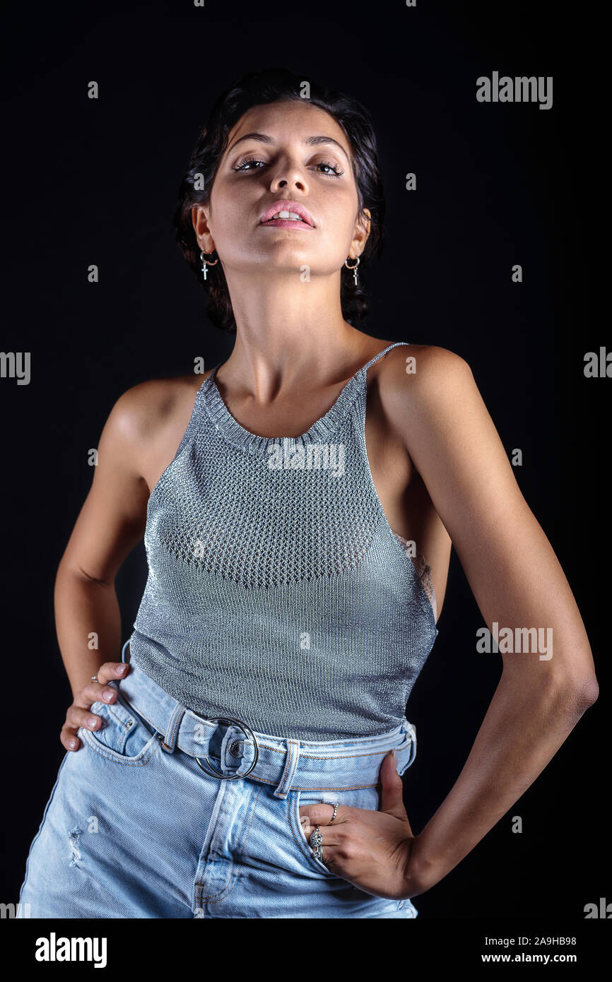 Informelle Besucherin, Jeans und Mieder, kurze Ärmel. Porträt einer Frau auf einem schwarzen Hintergrund, Brasilianische Staatsangehörigkeit, dunkle Haut, brünett, helle Augen. Stockfoto