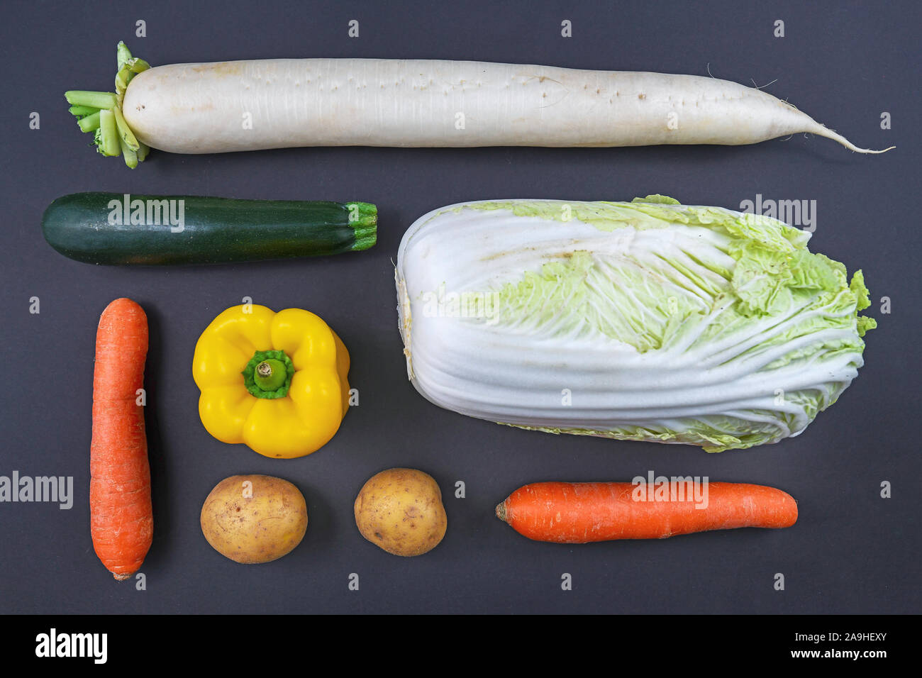 Ansicht von oben flach der verschiedenen Arten von rohem Gemüse wie Karotten, Paprika, Zucchini, Radieschen, Kartoffeln und Chinakohl auf dunklem Hintergrund Stockfoto