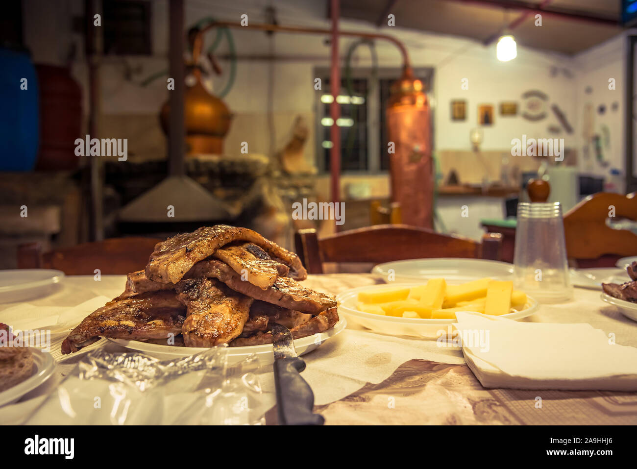 Ein Teller mit frisch gegrillten Steaks in Kazani, die traditionelle Destillation von Raki - tsipouro in Kreta, Griechenland Stockfoto