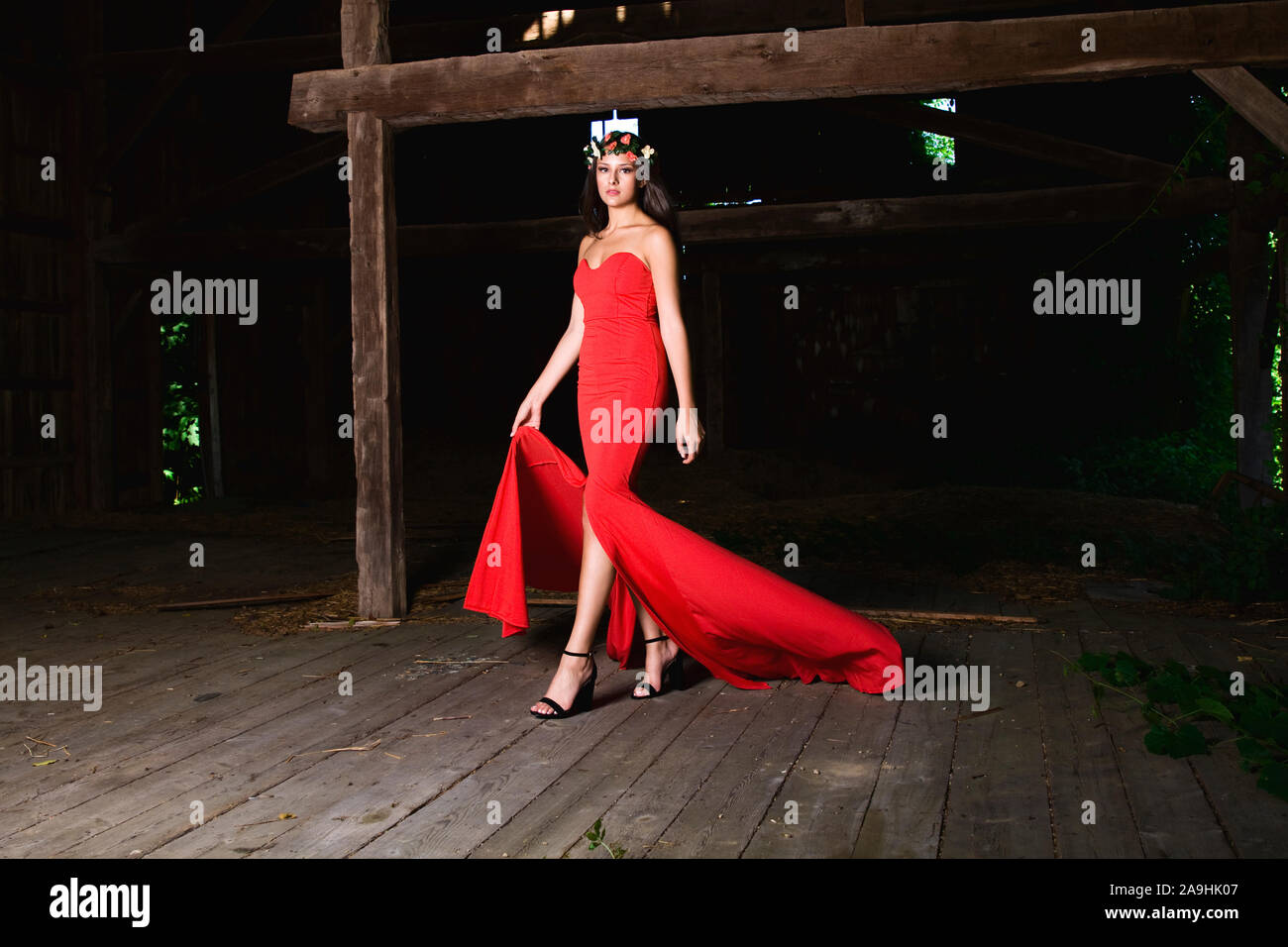 Outdoor High Fashion Foto der Frau in einem roten Abendkleid mit einem floralen Kopfstück Stockfoto