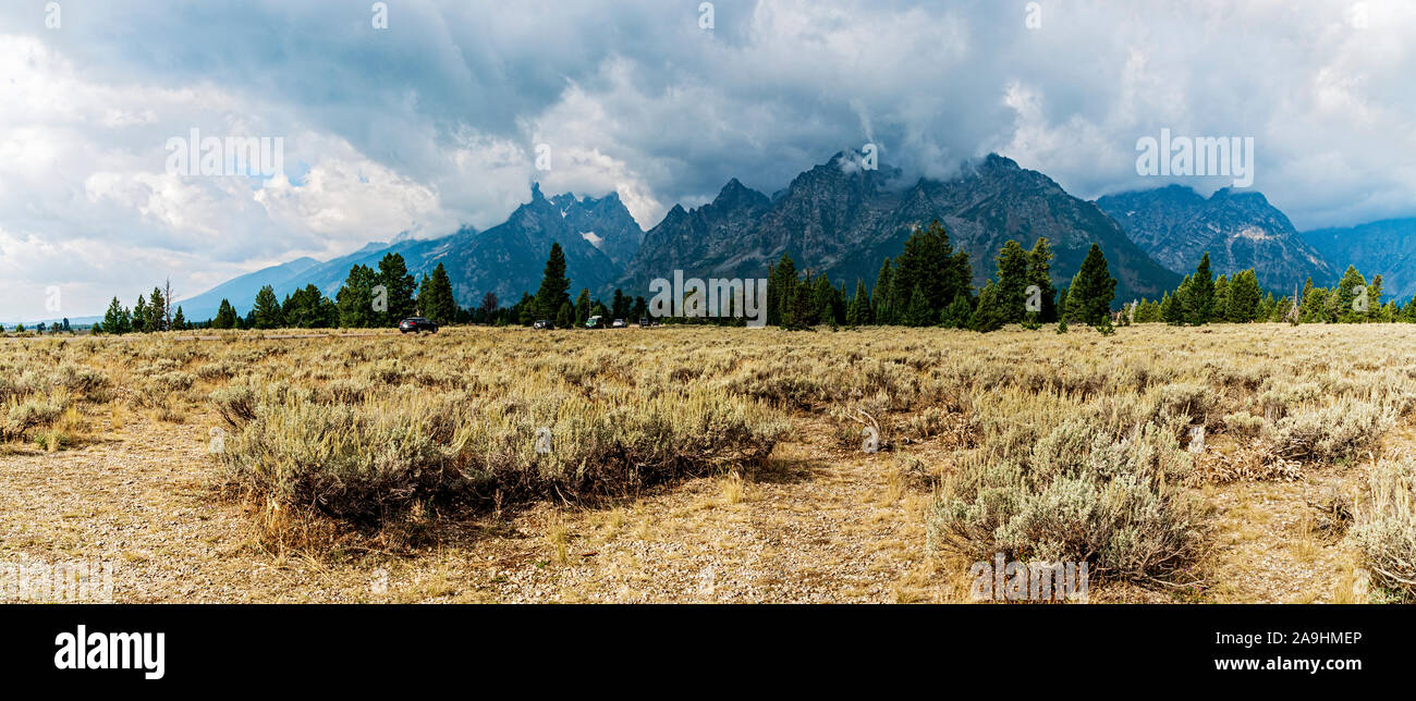 Panorama Blick auf den Grand Teton Rocky Mountains an einem stürmischen Tag mit Gewitterwolken, offenen Feldern, Wald und sagebrush. Stockfoto