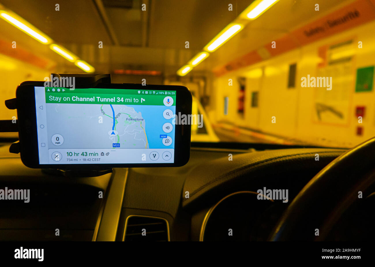 Blick von innen auf ein Auto eines Shuttle-Wagens, der die Personenkraftwagen durch den Kanaltunnel transkortiert. Ein GPS-Satellitennavigationsgerät für die Armaturenbrettmontage zeigt den Weg. Stockfoto
