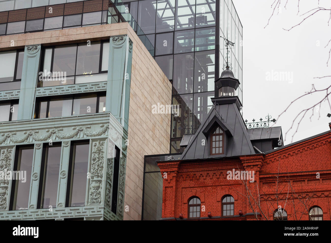 Alte und neue Architektur. Backsteinturm mit Wetterfahne und Glas Office Tower. Stockfoto