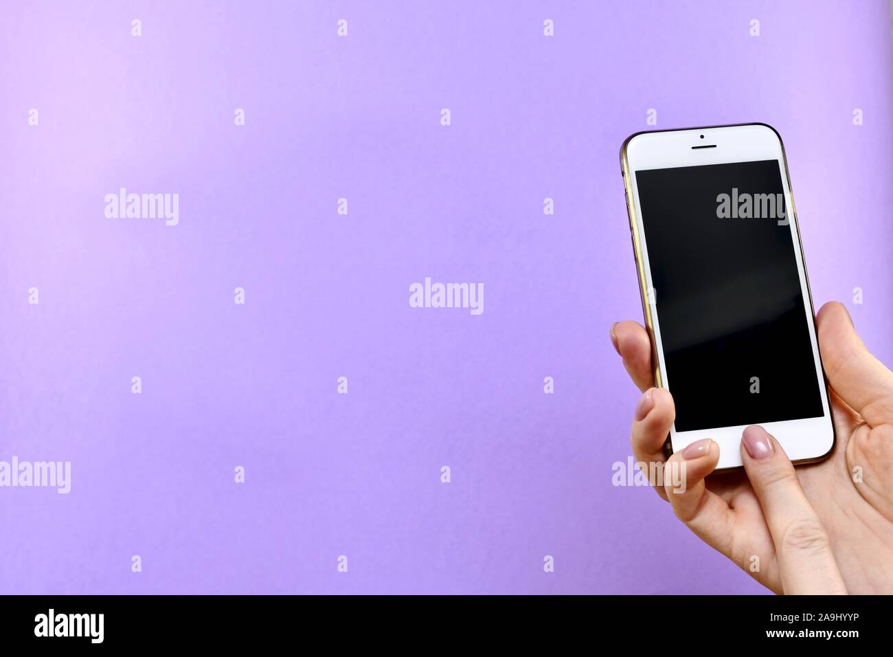 Ein Smartphone mit einem schwarzen Bildschirm ausgeschaltet in der Hand, die Schaltfläche ist mit dem Zeigefinger gedrückt. Stockfoto