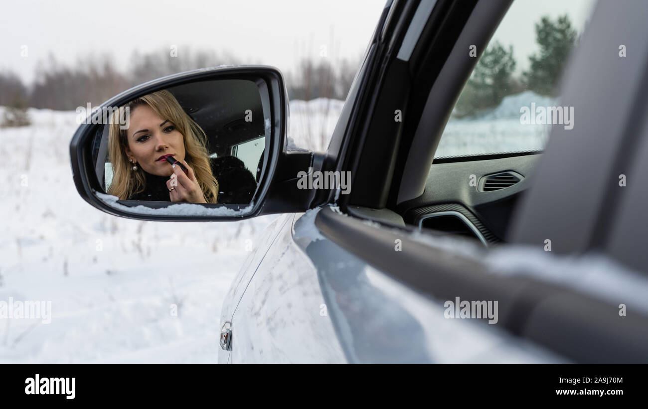 Blonde Frau, die in der Auto Rückspiegel und die Farbe der Lippen. Stockfoto