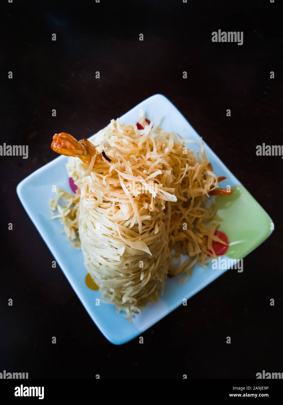 Gebratene Garnelen, die mit Nudeln bestrichen wurden, die als Udang Sanggul auf einem bunten Teller auf einem Holztisch bekannt sind. Stockfoto