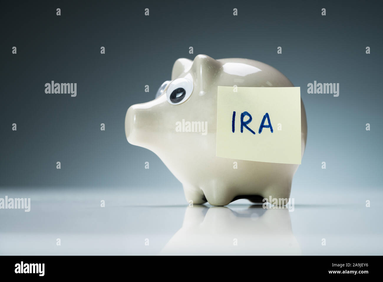 Eine weiße Sparschwein auf eine reflektierende Schreibtisch mit Ira Text auf Kleber Hinweis Stockfoto Eine weiße Sparschwein auf eine reflektierende Schreibtisch mit Ira Text auf Kleber Hinweis Stockfoto