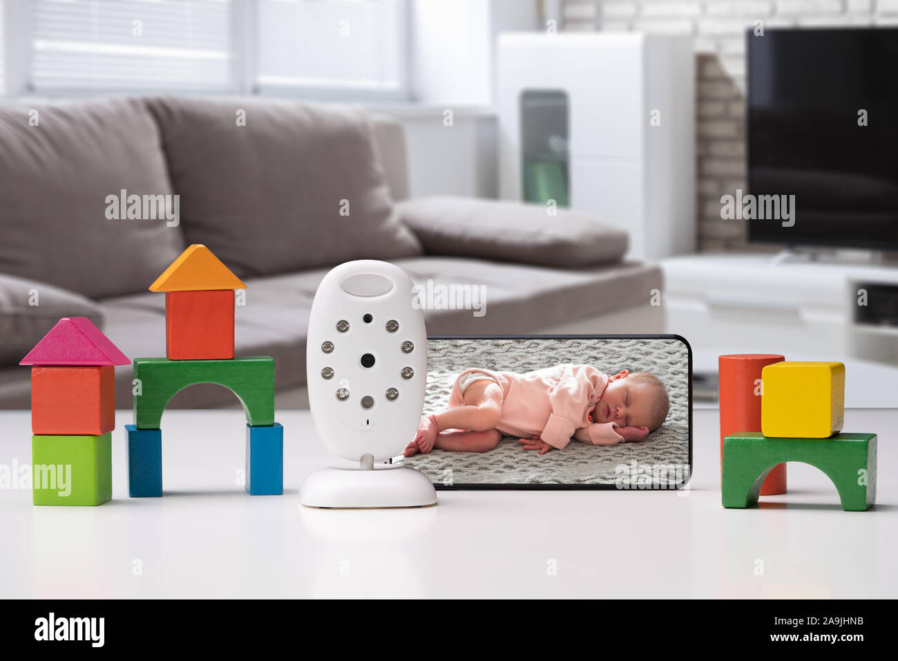 Bunte Spielzeug Häuser angeordnet in der Nähe von Mobiltelefon mit Baby Bild und drahtlose Kamera Stockfoto