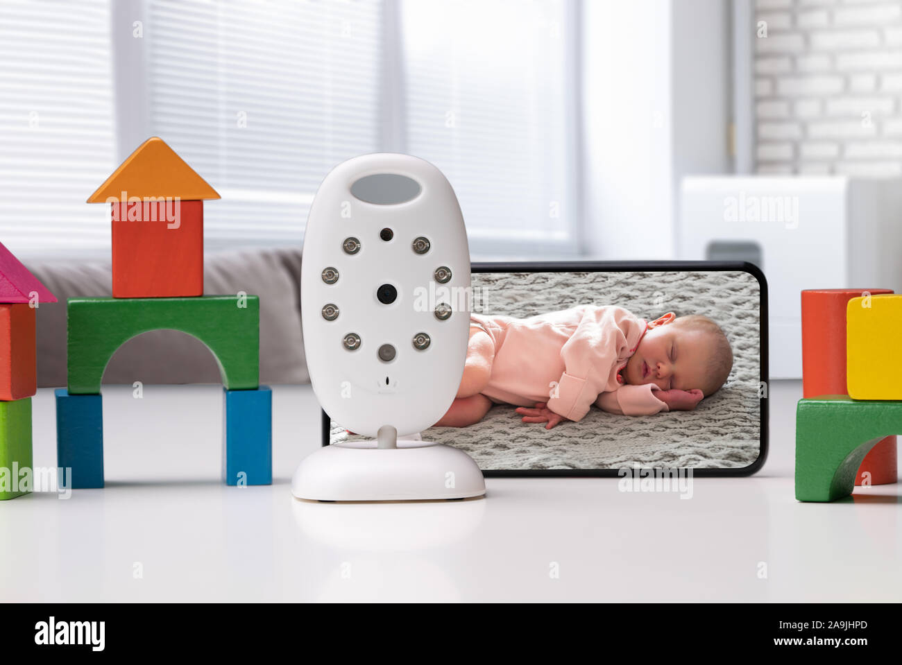Bunte Spielzeug Häuser angeordnet in der Nähe von Mobiltelefon mit Baby Bild und drahtlose Kamera Stockfoto