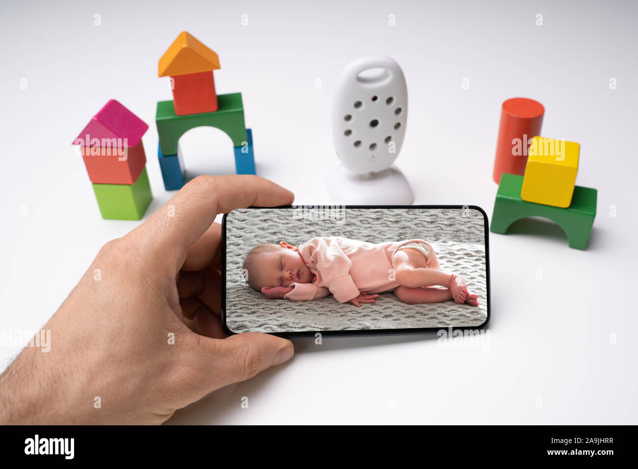 Person's Hand Handy mit Baby Bild in der Nähe von WLAN-Kamera Stockfoto