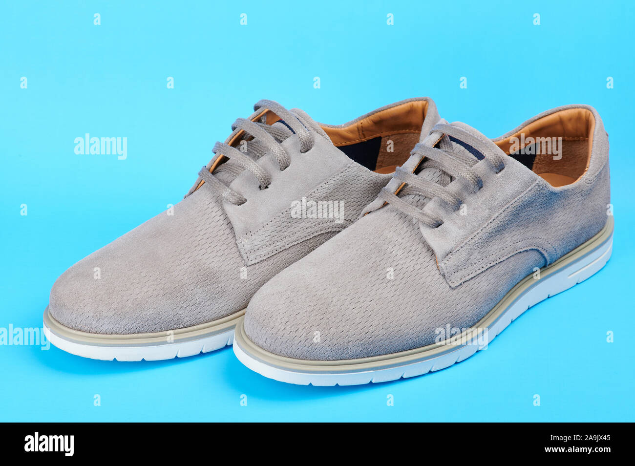 Paar moderne graue Schuhe Seitenansicht auf blauem Hintergrund isoliert Stockfoto