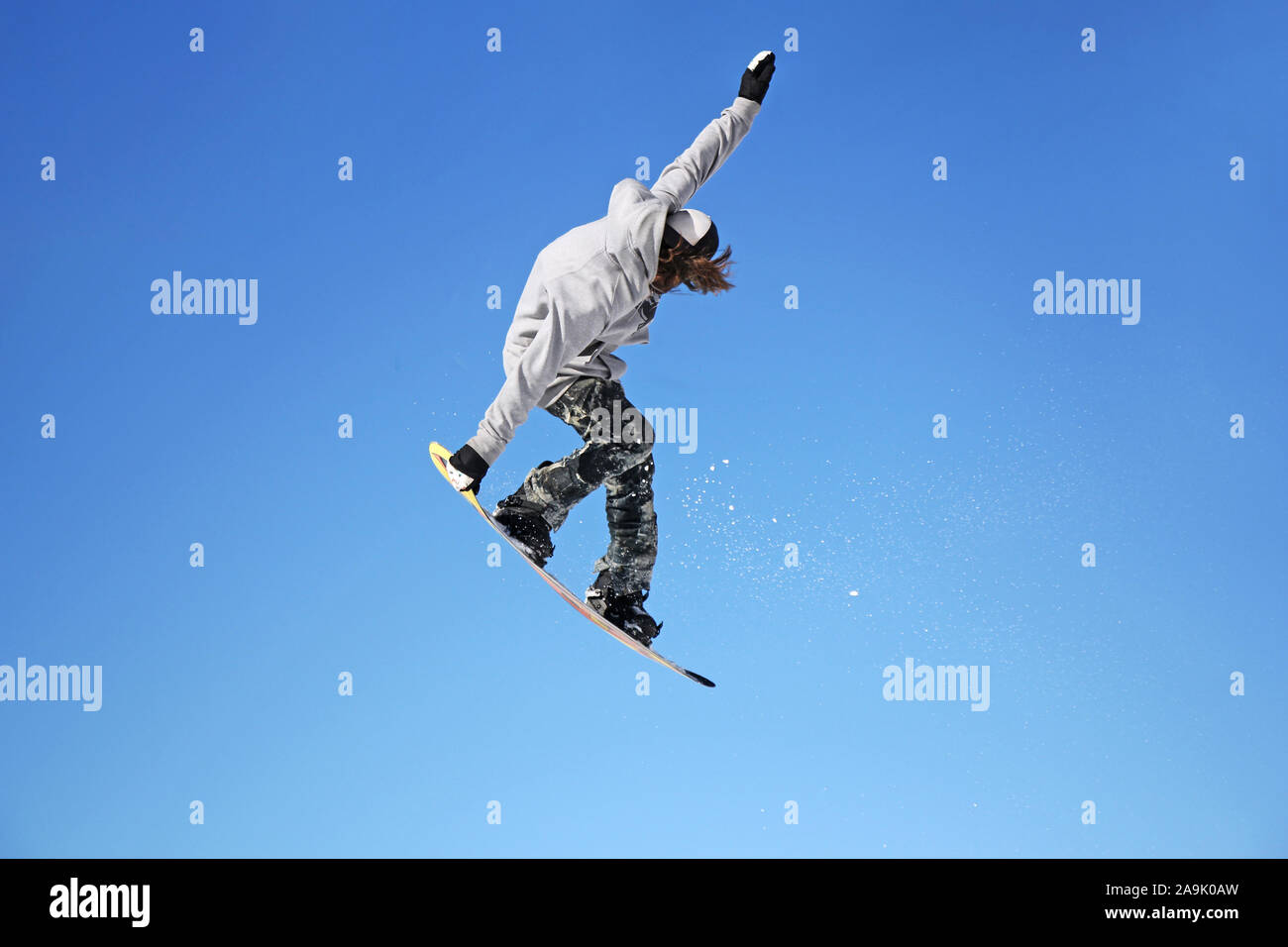 Snowboarder durch Luft mit blauen Himmel im Hintergrund springen Stockfoto