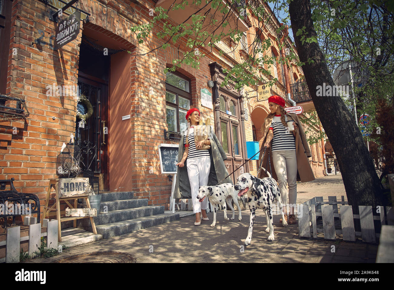 Zwei Mädchen in roten Barette sind Spaziergänge durch die Stadt mit Hunden der Dolmatian Rasse. Stockfoto