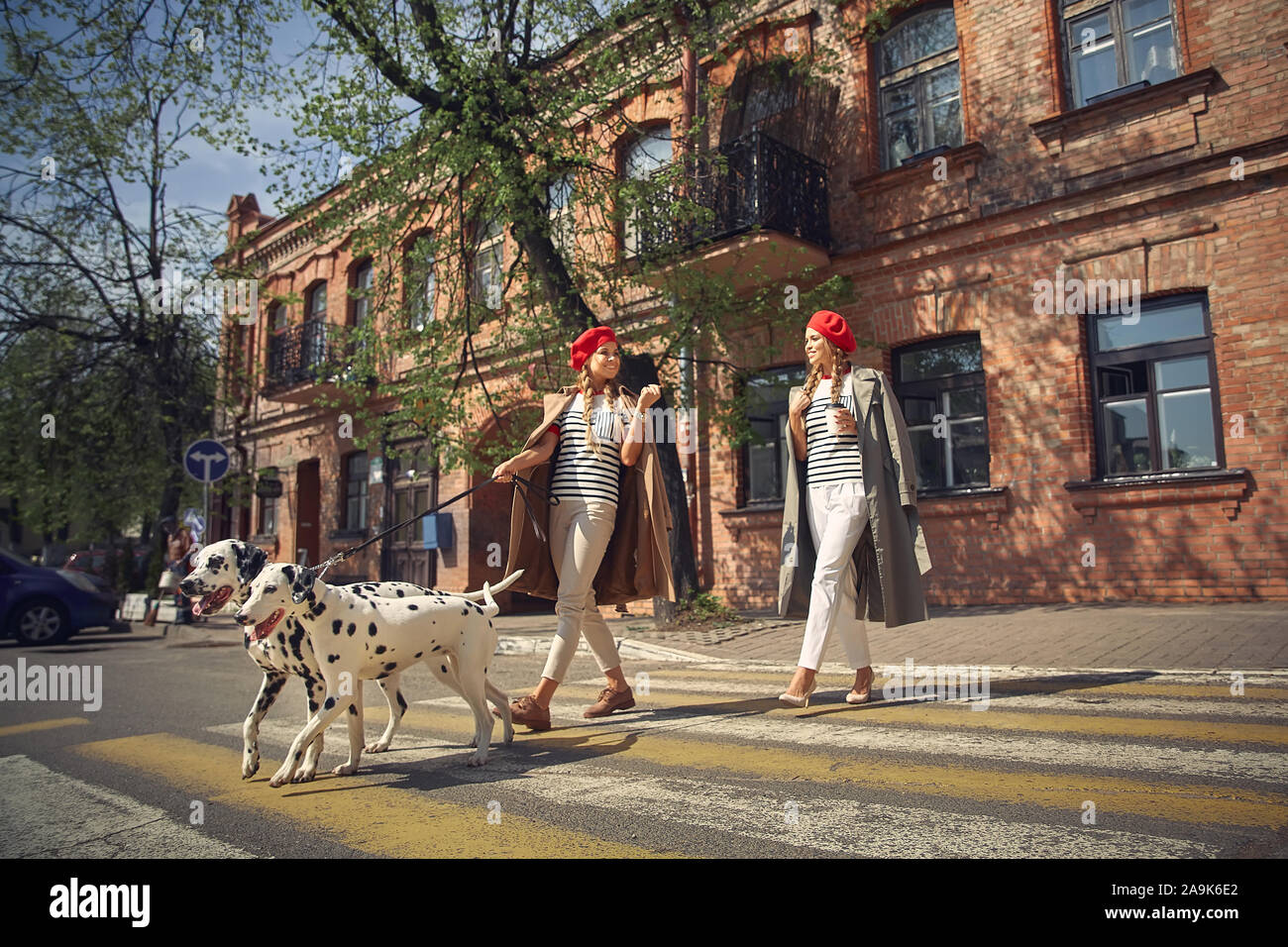 Zwei Mädchen in roten Barette sind Spaziergänge durch die Stadt mit Hunden der Dolmatian Rasse. Stockfoto