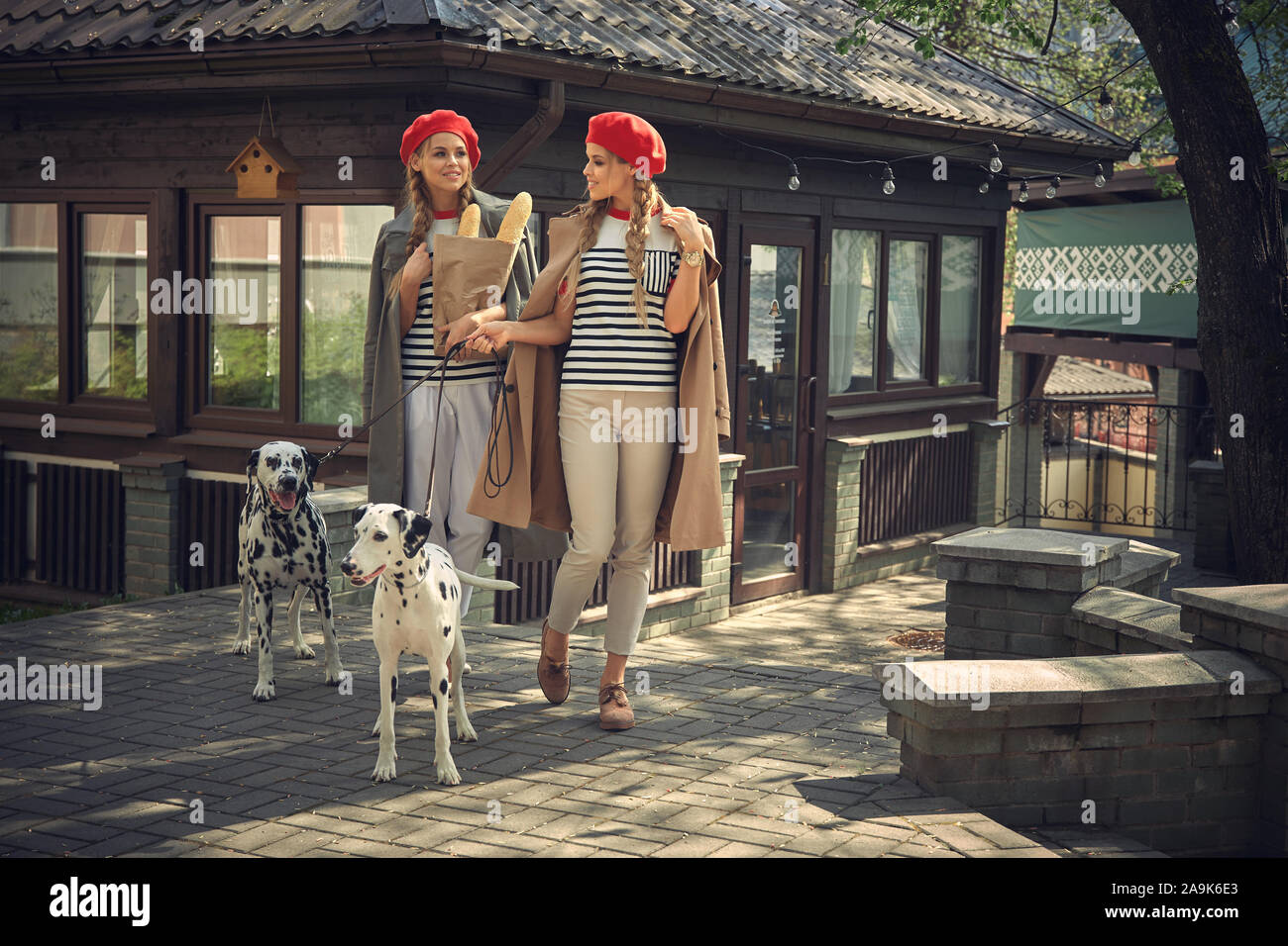 Zwei Mädchen in roten Barette sind Spaziergänge durch die Stadt mit Hunden der Dolmatian Rasse. Stockfoto