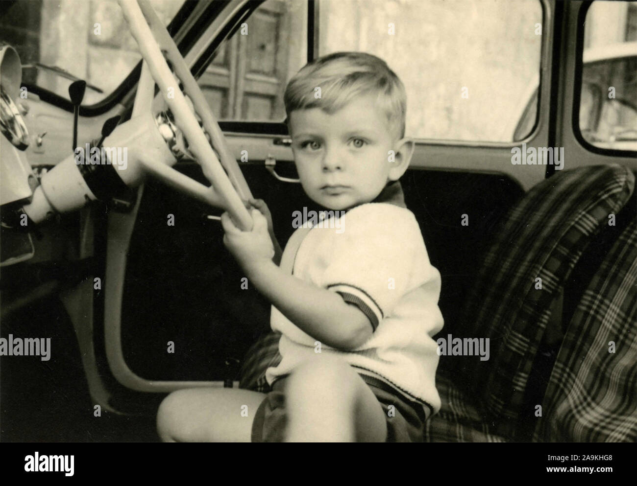 Ein Kind sitzt hinter dem Steuer eines Autos, Italien Stockfoto